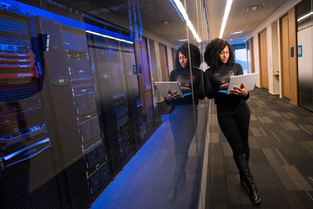 Two technicians reviewing laptops in a data centre aisle
