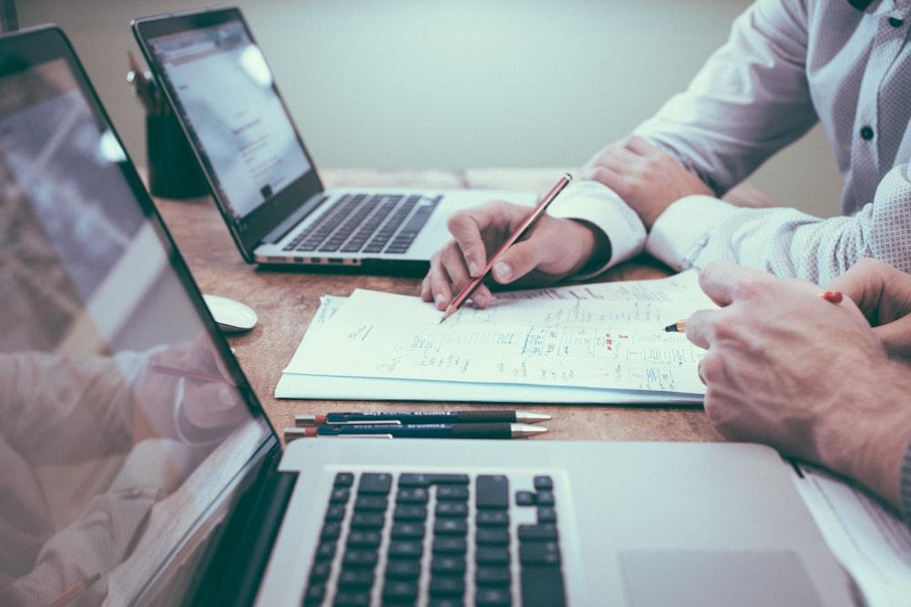 Hands taking notes beside a laptop on a desk