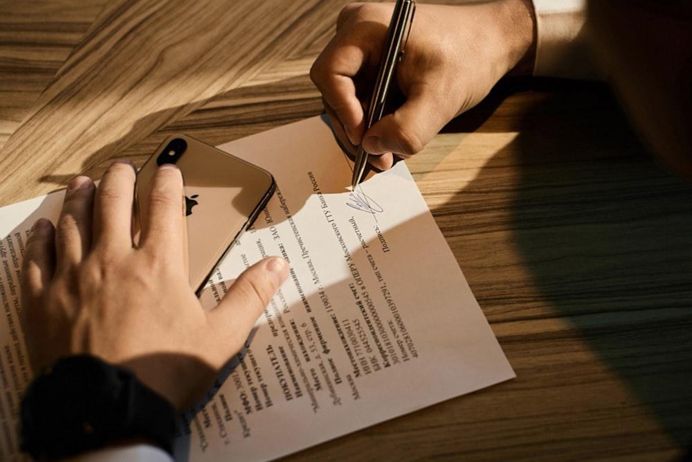 A person signing paperwork on a desk, seen from above