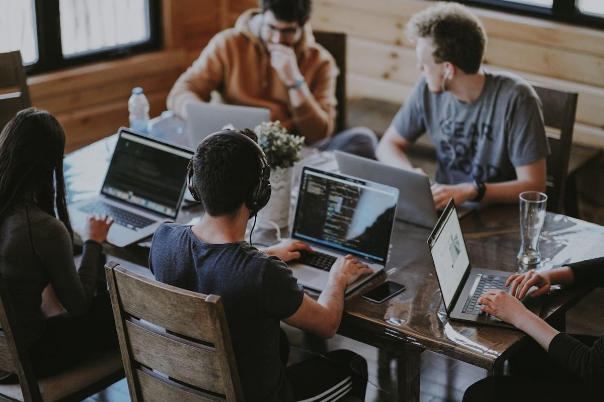 A team working side by side on laptops around a shared table